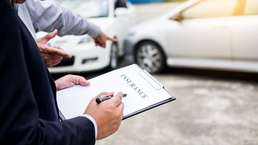 An insurance adjuster and a client discussing a car accident, with the adjuster holding a clipboard labeled 'INSURANCE' and pointing towards a row of cars, presumably involved in the incident.
