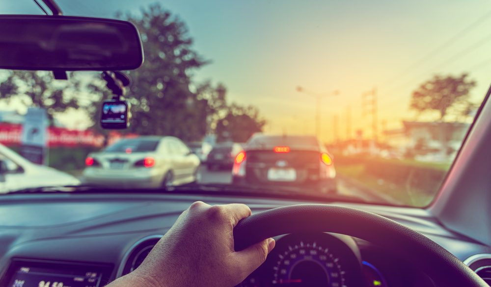 A motorist steers a car in traffic while wondering how long a car accident can stay on your driving record in Washington State. 