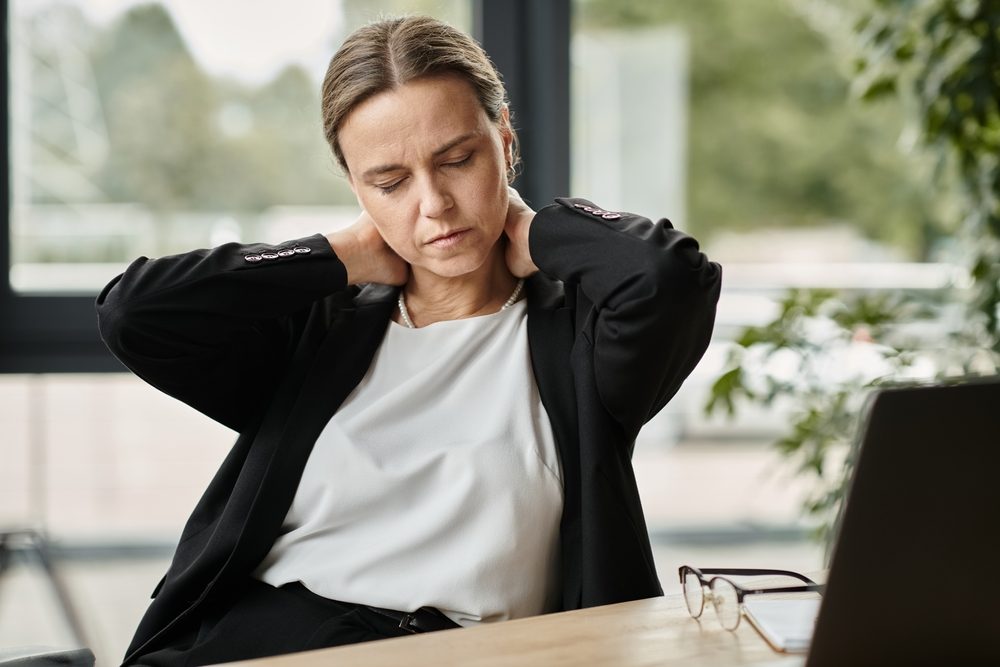 A woman rubs her neck and wonders when it is too late to go to the doctor after a car accident. 