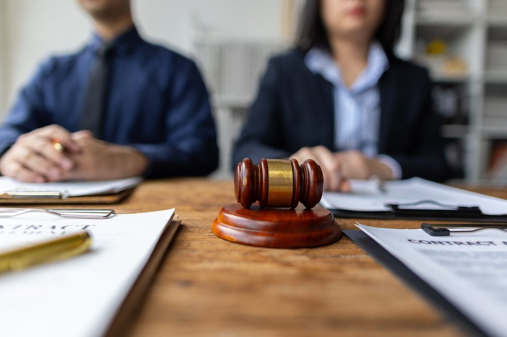 A gavel on a table in front of two plaintiffs. How long does a personal injury lawsuit take?