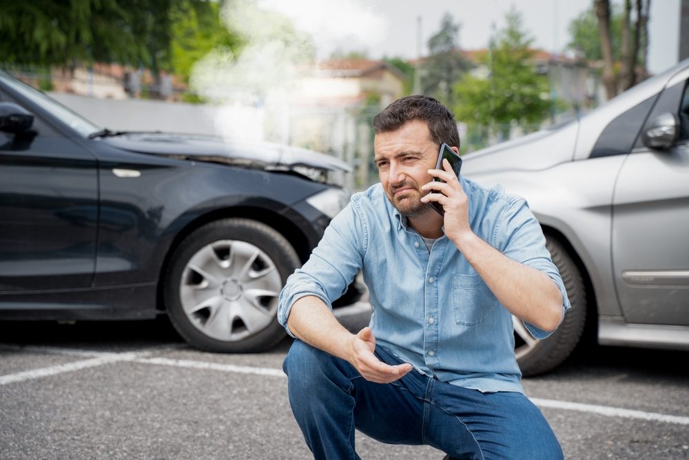 A man on the phone in front of a car accident. Who is responsible for a rental car in an accident?